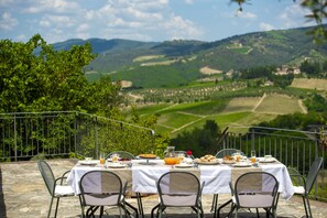 A table set for breakfast with a scenic view of rolling hills and vineyards. - Il Casello Country House (Greve in Chianti)