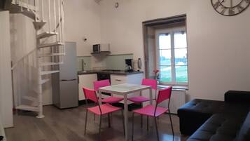 A compact kitchen with a dining area, a staircase, and a view through a window.
