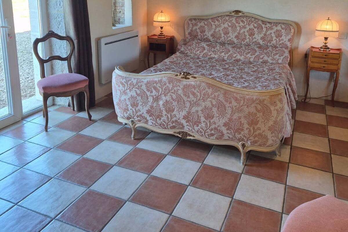 Quarto com uma cama, duas mesas de cabeceira, uma cadeira e uma janela.