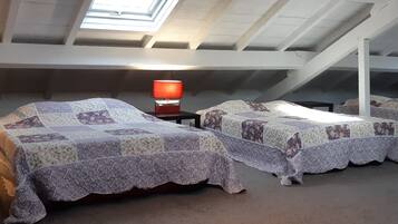 Ein Schlafsaalzimmer mit zwei Betten, einem Dachfenster und einem Tisch mit einer Lampe.
