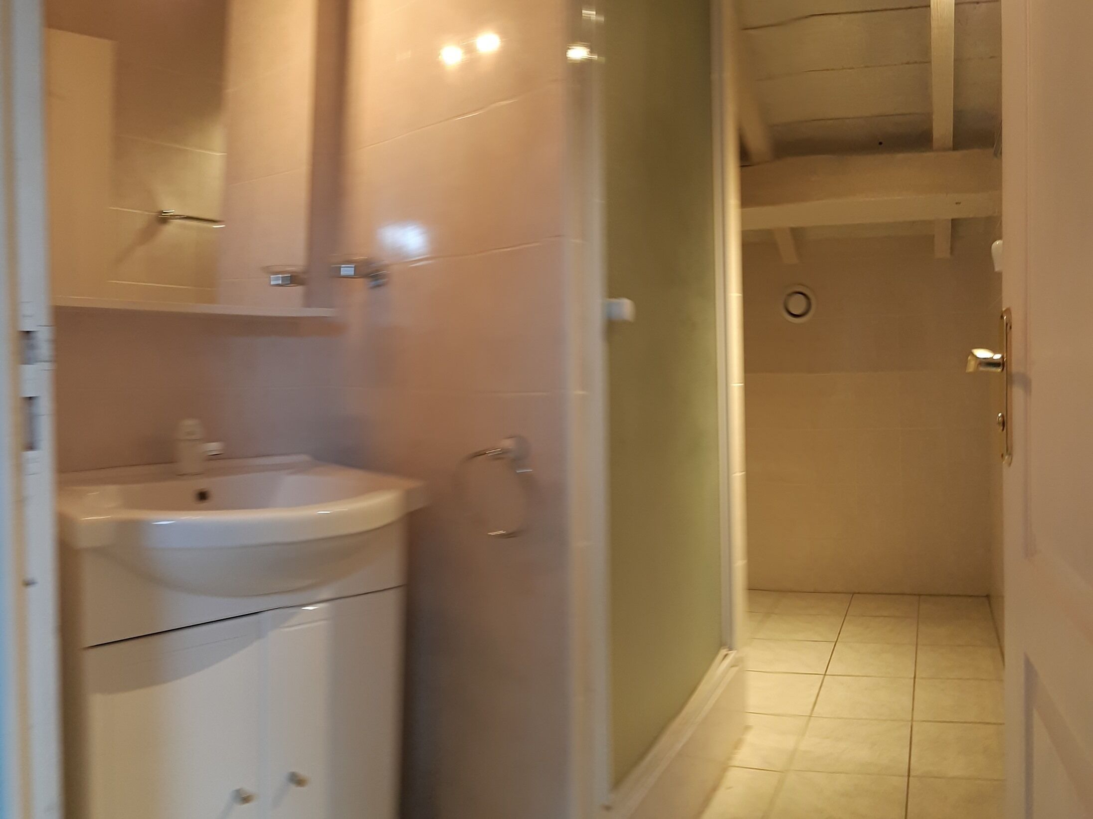 Casa de banho com lavatório, espelho e zona de duche.