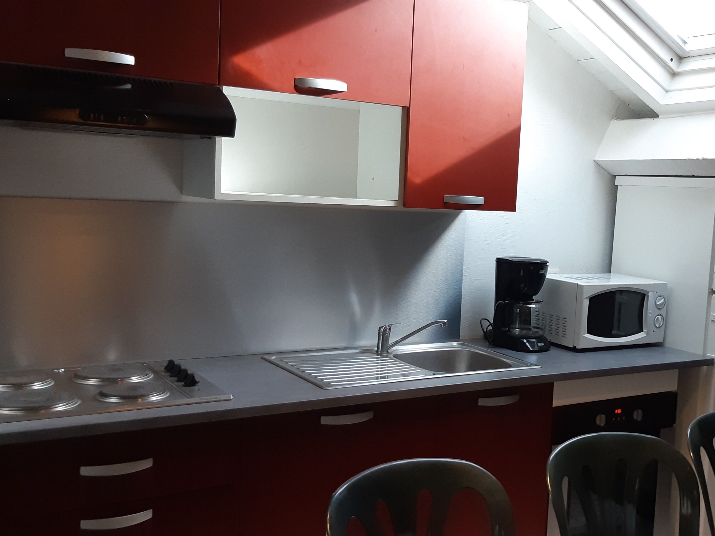 A compact kitchen with a microwave, coffee maker, and a sink.