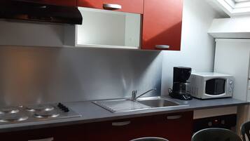 A compact kitchen with a microwave, coffee maker, and a sink.