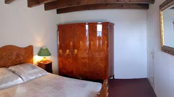 Ein Schlafzimmer mit einem hölzernen Kopfteil, einem großen Holzschrank, einer grünen Lampe und einem roten Teppich.