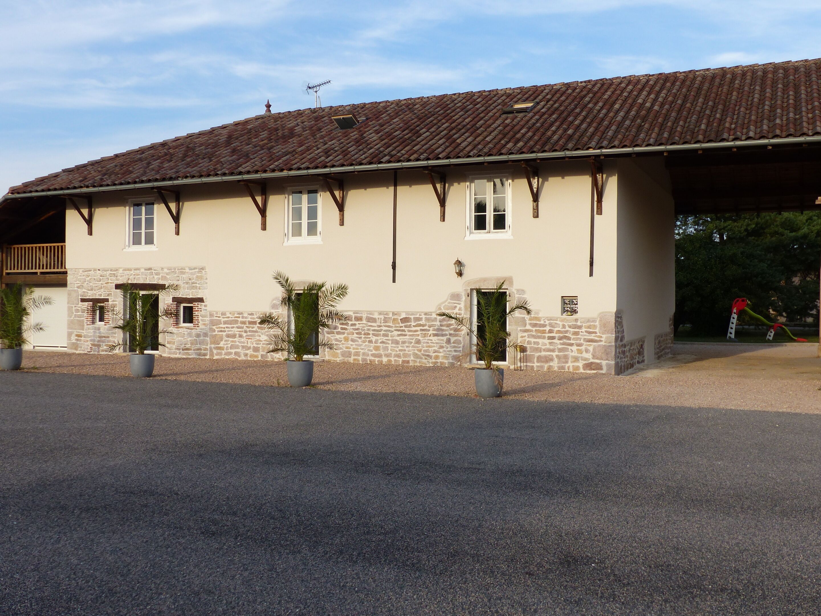 A two-story building with a stone facade, multiple windows, and a tiled roof.
