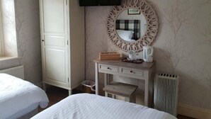 A hotel room with two beds, a wardrobe, a vanity with a mirror, a flat-screen TV, and a radiator. - Queen Catherine Hotel (Northallerton)