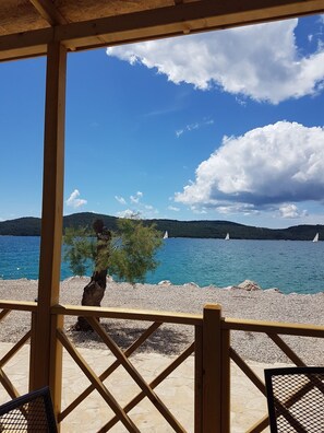 A wooden pergola overlooking a pebble beach with a clear view of the sea and sailboats. - Amadria Park Camping Mobile Homes  (Sibenik)