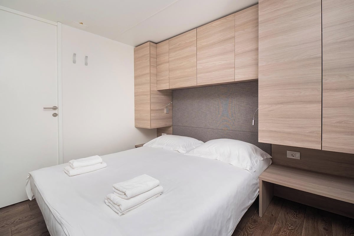 Ein Schlafzimmer mit einem Bett, weißer Bettwäsche und Holzschränken.