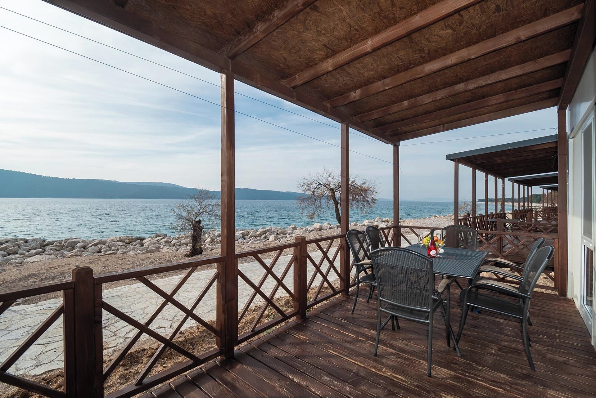 A wooden deck with outdoor seating overlooking a lake.