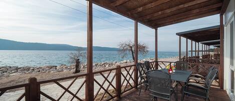 A wooden deck with outdoor seating overlooking a lake.