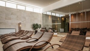 A modern spa area with wicker lounge chairs, a large mirror, and a view of the spa entrance.