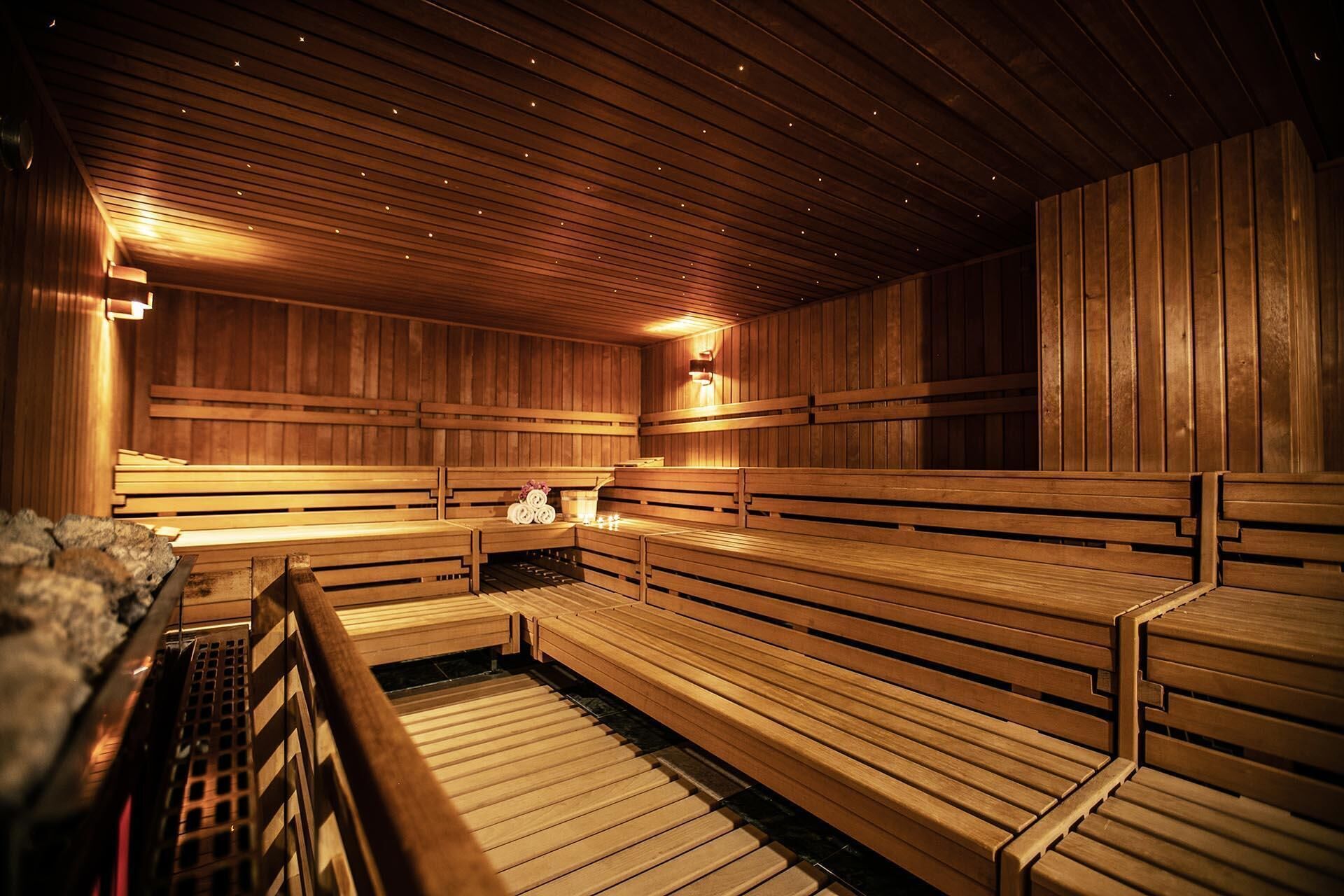 A sauna with wooden benches and a bench with a towel and a small container.