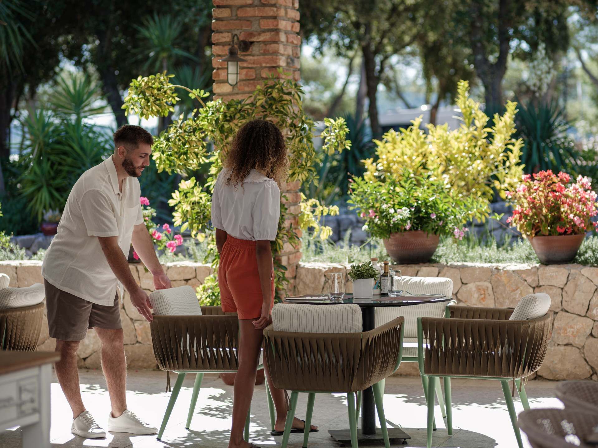 Patio esterno con sedie in vimini, un tavolo e piante in vaso.