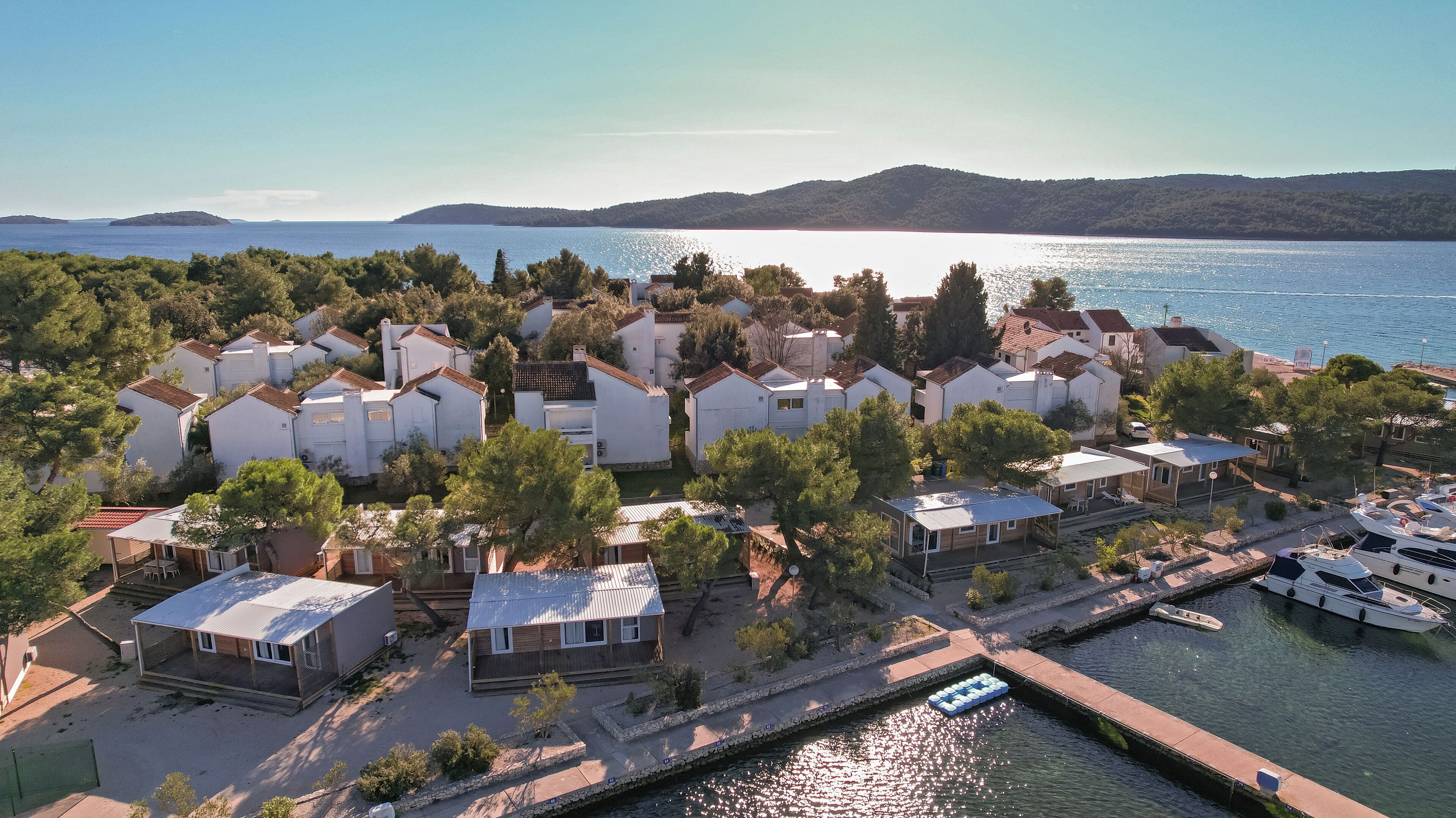 A coastal residential area with houses, a marina, and a view of the sea.