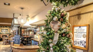 A Christmas tree with ornaments and a sign next to a bar area in a hotel. - Pooley Bridge Inn (Penrith)