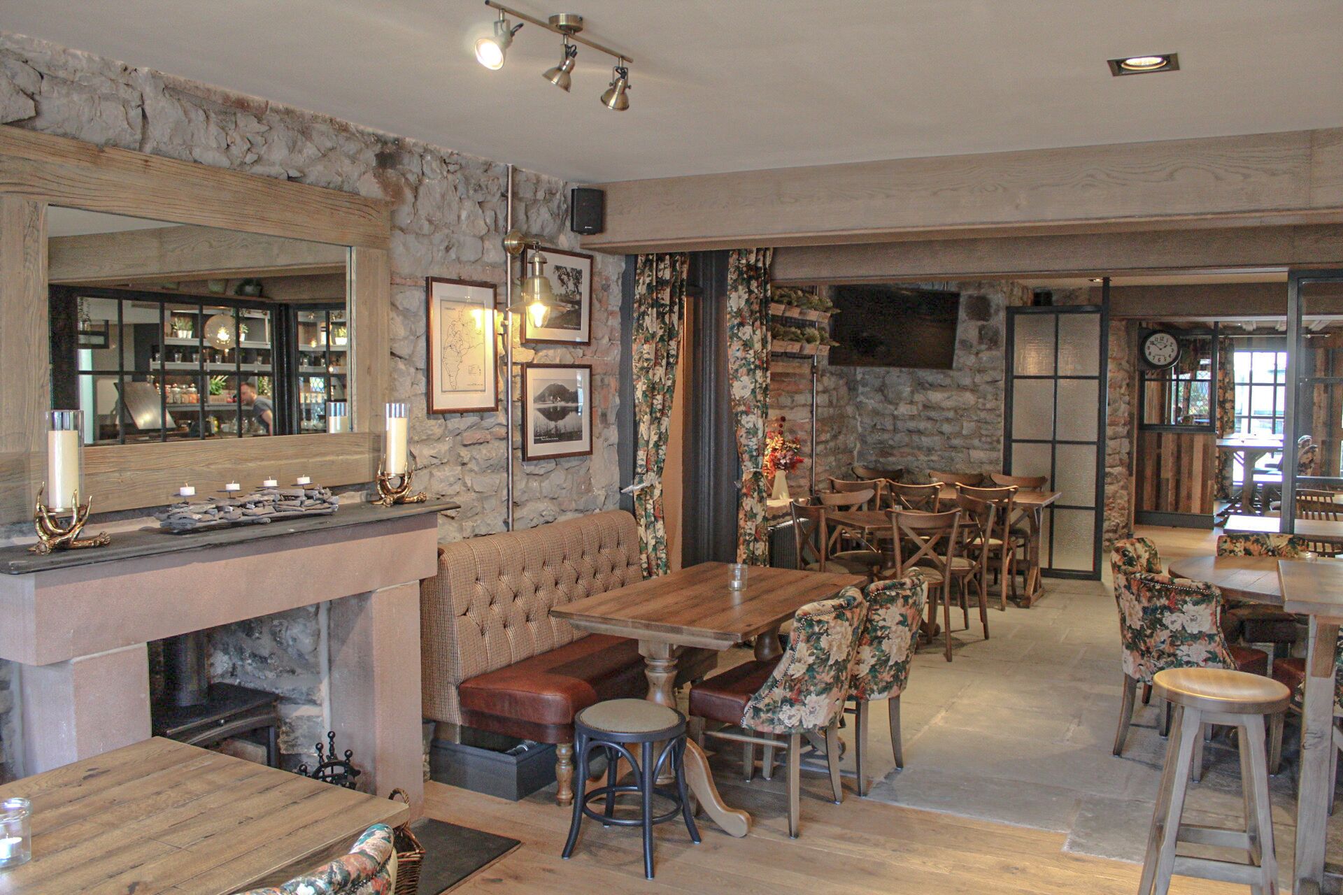 A cozy restaurant with a stone wall, wooden furniture, and a fireplace.