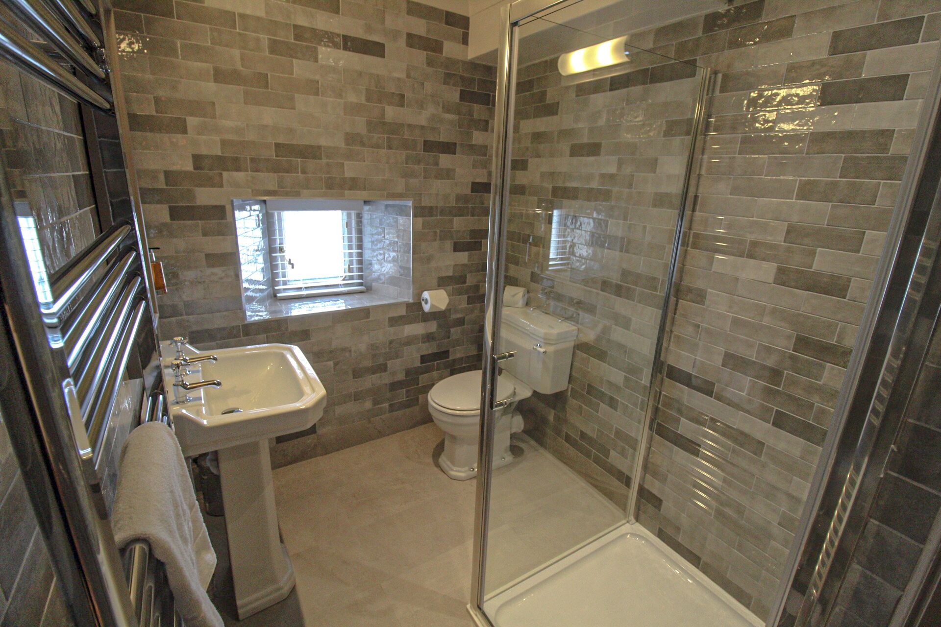 Un baño con cabina de ducha de vidrio, lavamanos e inodoro.