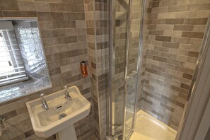 A bathroom with a glass-enclosed shower, a sink, and a mirror. - Pooley Bridge Inn (Penrith)
