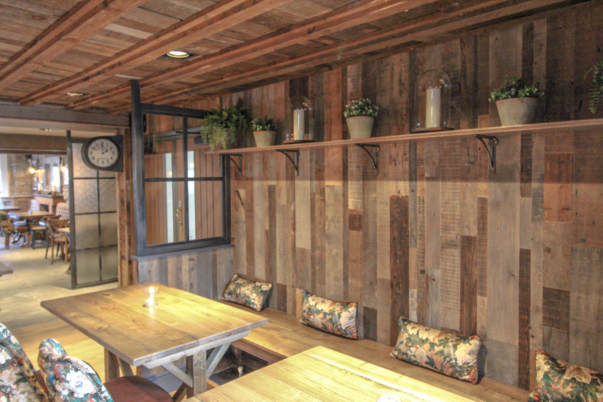 Un interior rústico con paredes de madera, una mesa de madera y bancos con cojines estampados.