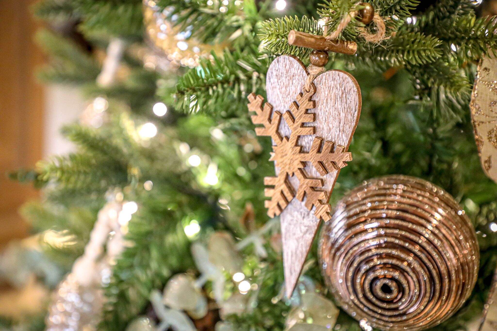 A Christmas tree with ornaments including a wooden angel and a spiral decoration.