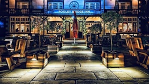 The exterior of the Pooley Bridge Inn with a stone pathway leading to the entrance, outdoor seating, and a sign above the entrance. - Pooley Bridge Inn (Penrith)