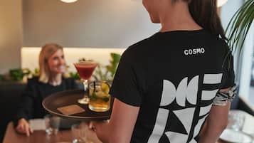 Une personne servant une boisson à une table, en tenant un plateau.