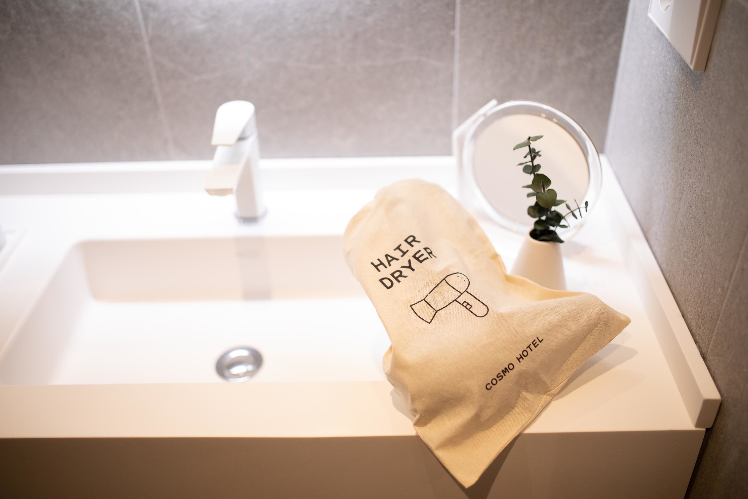 Een wastafel in een badkamer met een handdoek aan de zijkant, een kleine potplant en een spiegel.