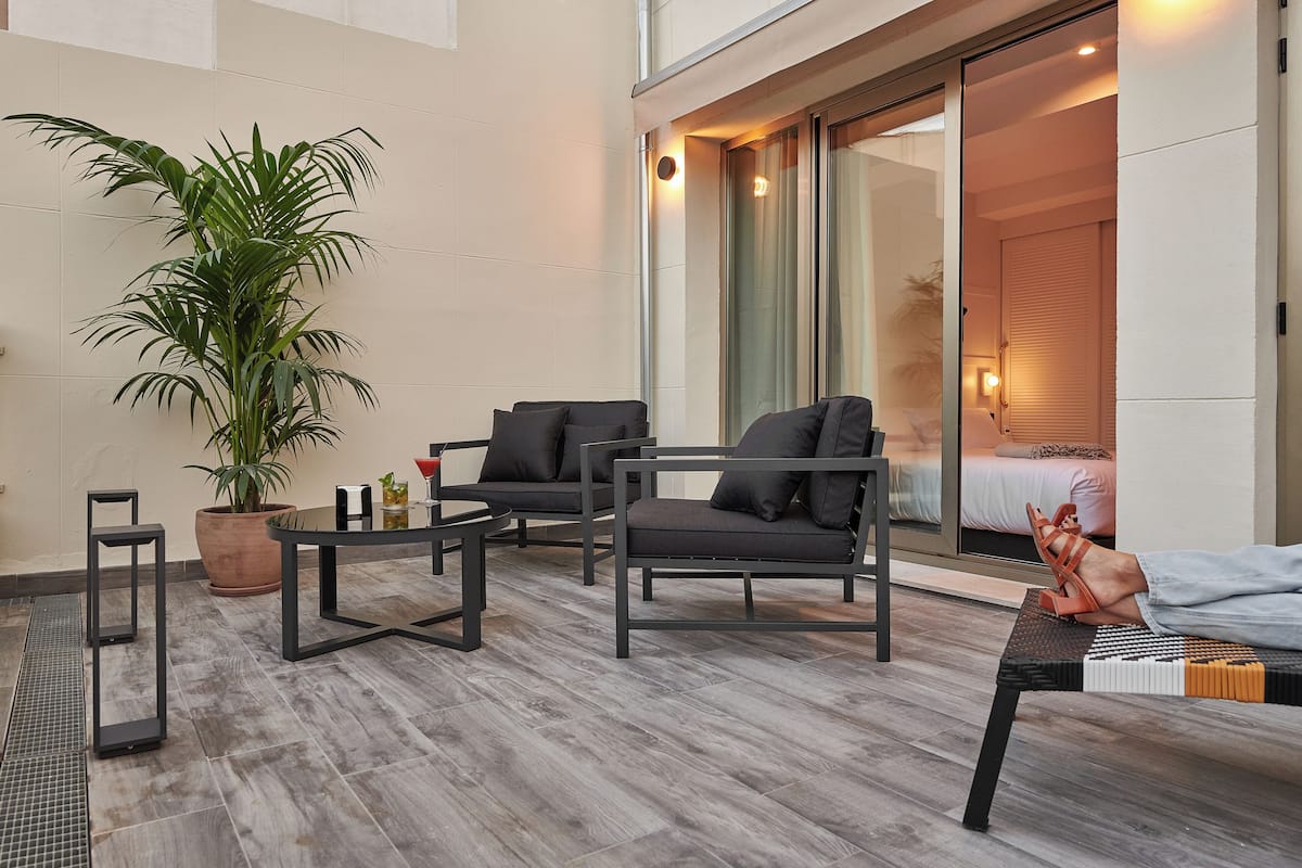 Un salón moderno con sofá, sillones, una mesa de centro y una planta en maceta.