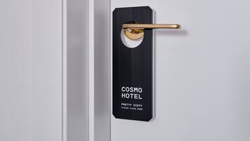 A door with a black and gold sign that reads "COSMO HOTEL" and "PRETTY DIRTY PLEASE CLEAN ROOM".