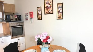 A dining area with a round wooden table, four chairs, a vase of flowers, and a welcome sign.