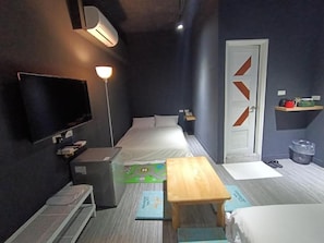 Une chambre d’hôtel de taille réduite, comprenant un lit, une table de chevet, une télévision et un petit coin salon.
