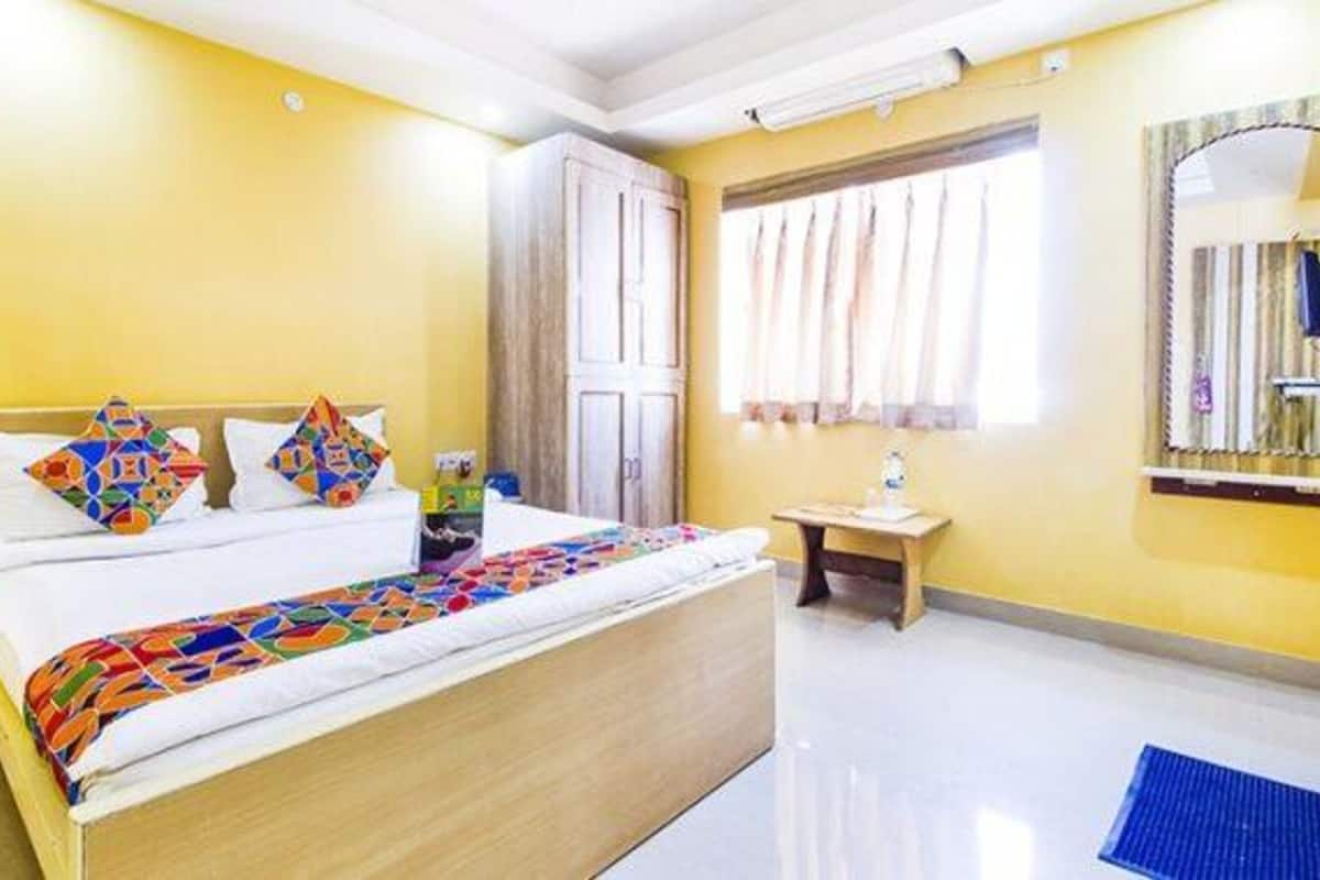 A hotel room with a bed, a small table, and a window with curtains.