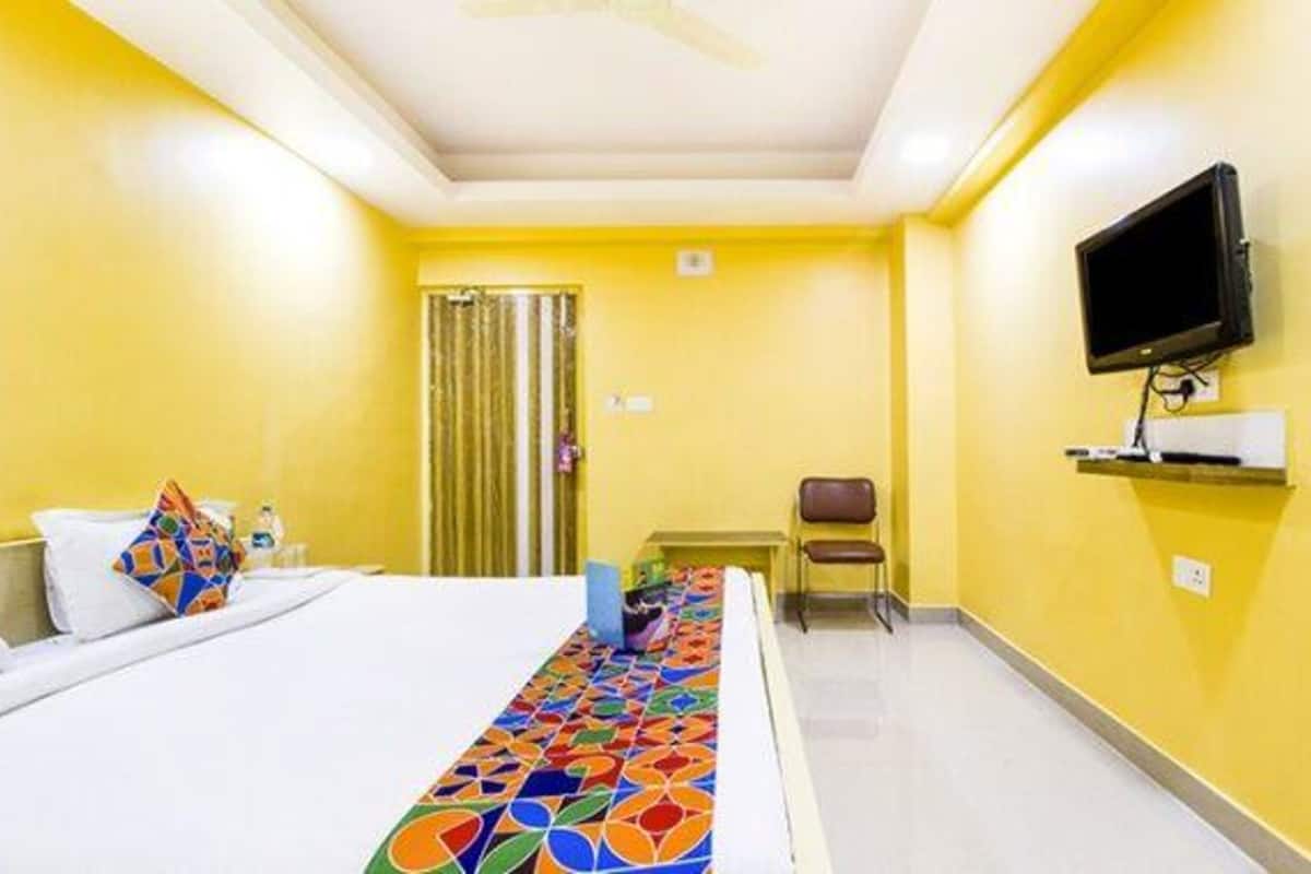 A hotel room with a bed, a television mounted on the wall, a small table, and a chair.