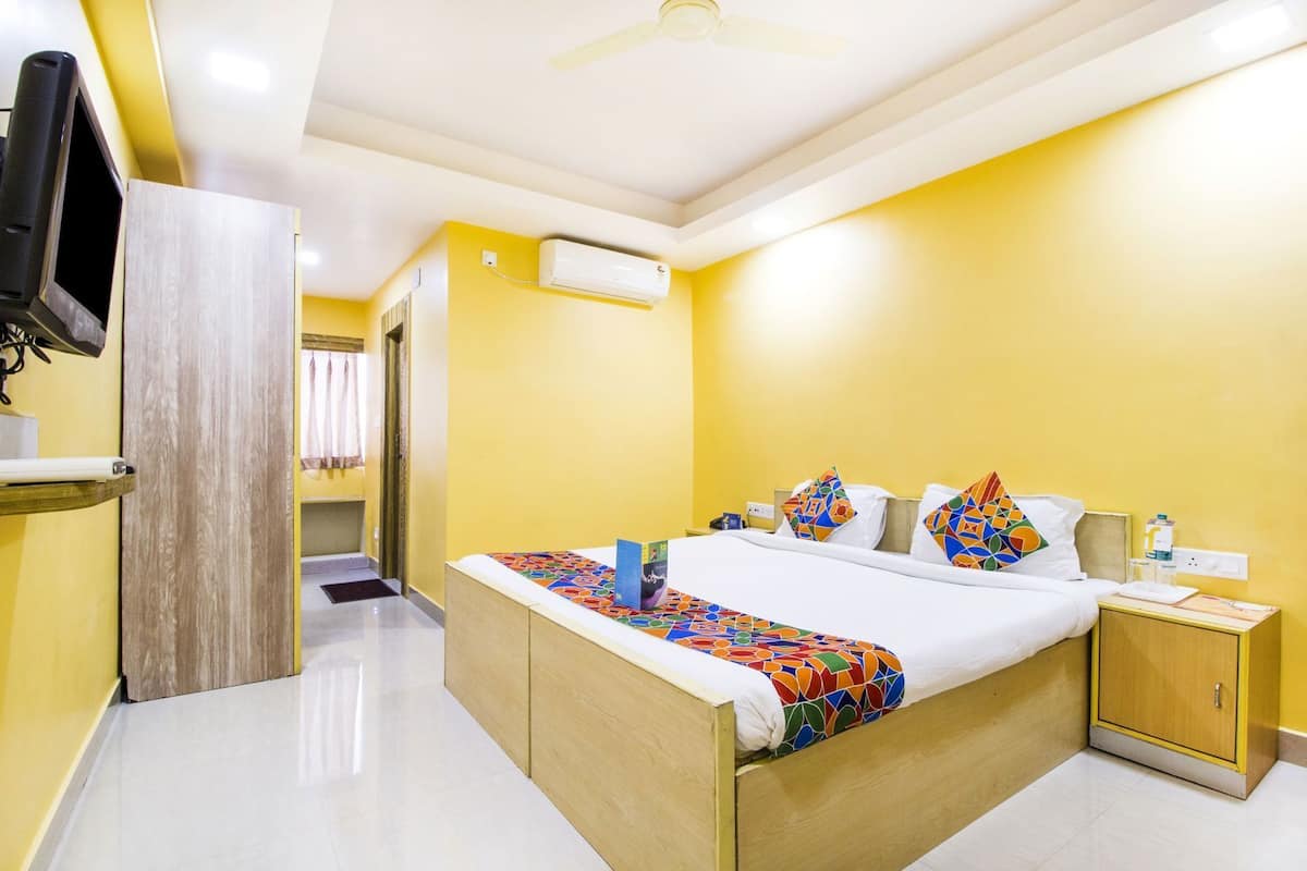 A hotel room with a bed, bedside table, nightstand, and a television mounted on the wall.