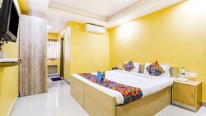 A hotel room with a bed, a bedside table, a TV, and a wardrobe. - FabHotel Amaltas (Ranchi)