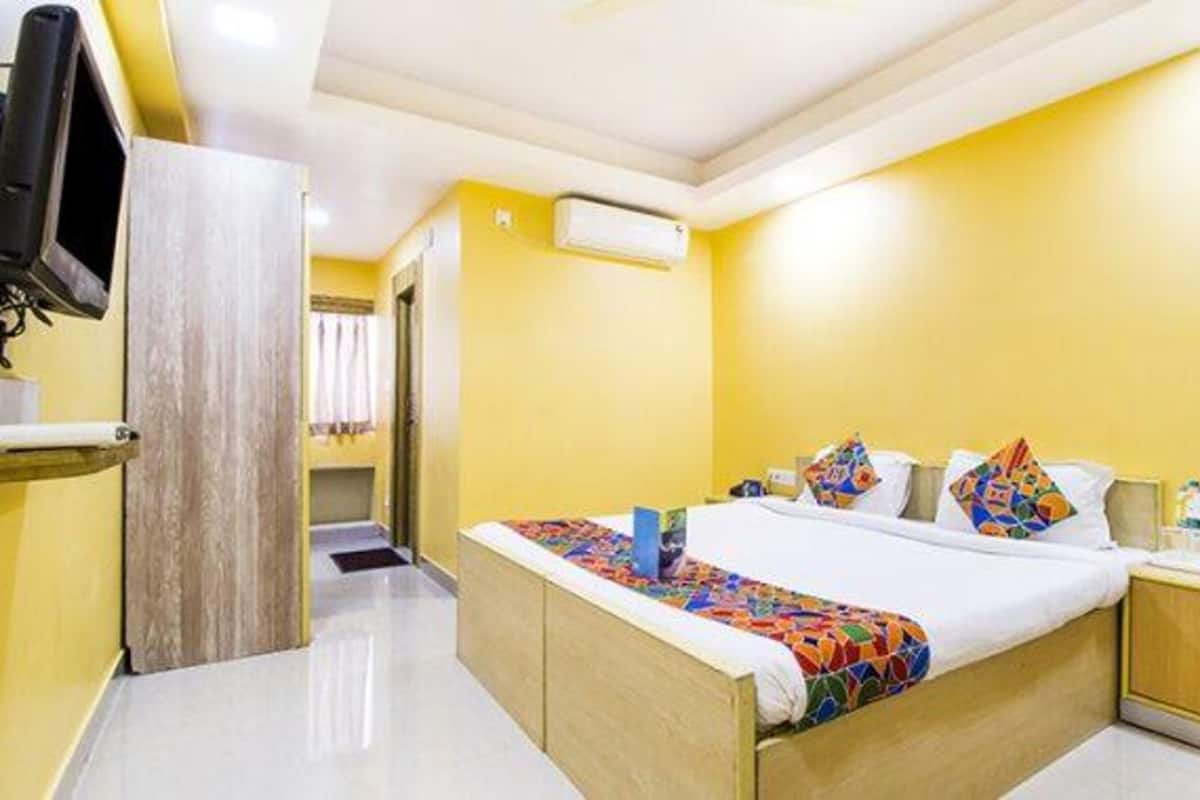 A hotel room with a bed, a bedside table, a TV, and a wardrobe.