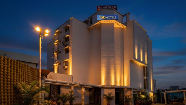 A modern hotel with a flat roof, a sign for 'Amaltash' and 'fabHOTELS', and a paved entrance area with potted plants. - FabHotel Amaltas (Ranchi)