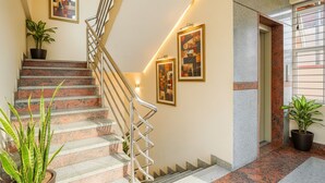 A staircase with metal railings, potted plants, and framed artwork on the walls. - FabHotel Amaltas (Ranchi)