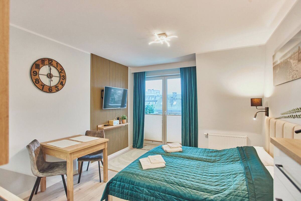 Ein Hotelzimmer mit Bett, Schreibtisch, Stuhl, Fernseher und einem Fenster mit Vorhängen.