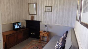 A living room with a fireplace, a television, a sofa, and a small wooden side table.