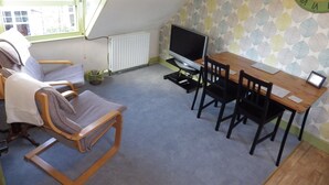 A small, triangular room with a television, a wooden table, and a chair. - Ryvington Apartments (Abergavenny)
