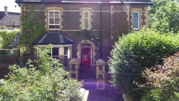 A two-story stone house with a red door and a small porch. - Ryvington Apartments (Abergavenny)