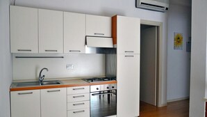 A compact kitchen with white cabinets, a stainless steel sink, and a gas stove. - Residence Rivaverde (Ravenna)