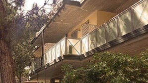 A multi-story building with balconies, surrounded by trees and a fence. - Residence Rivaverde (Ravenna)
