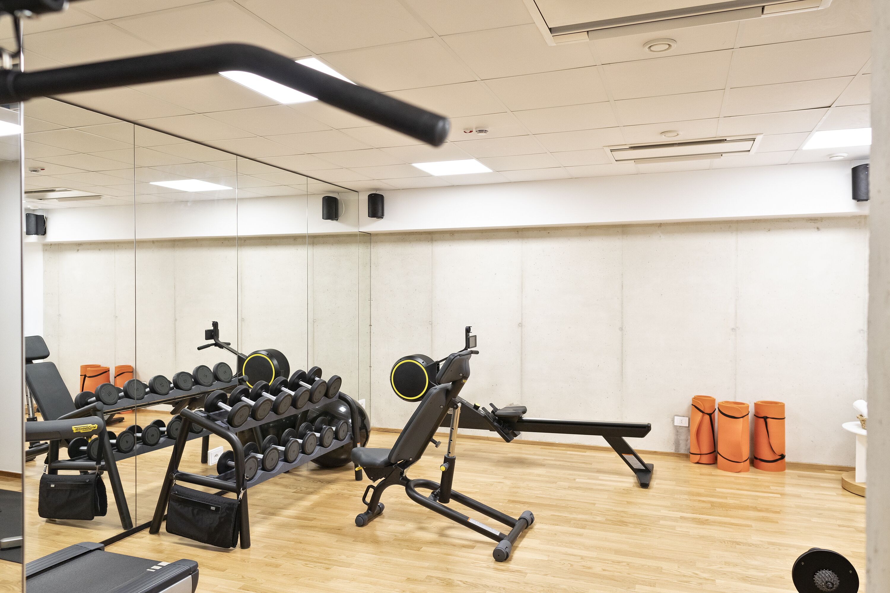 Une salle de sport équipée de matériel d’exercice, d’un miroir et de bacs de rangement orange.