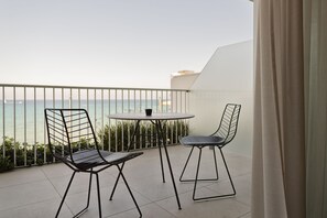 Varanda com mesa redonda e duas cadeiras, com vista para um corpo de água.