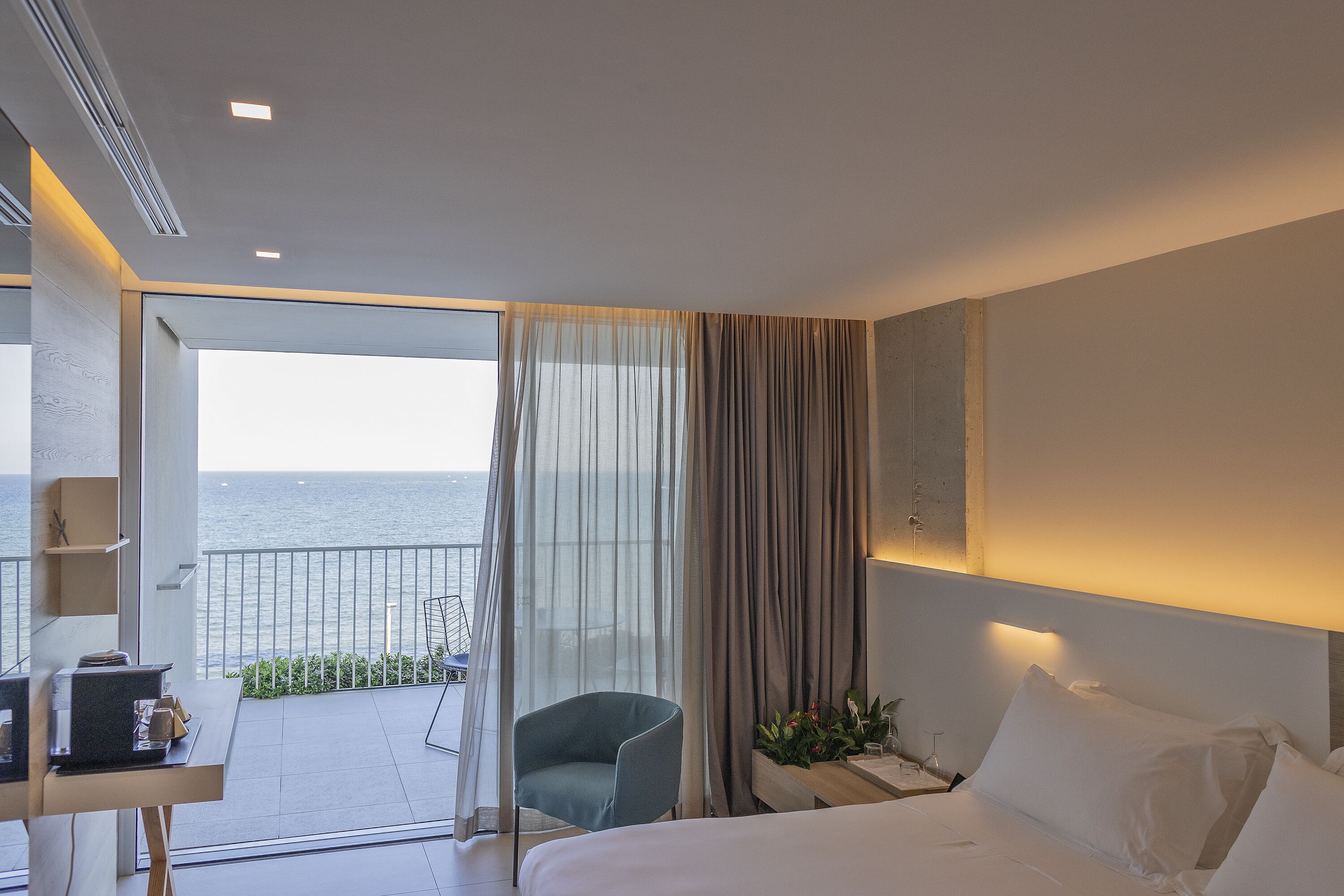 Una camera d'hotel con un letto, una scrivania, una sedia e vista mare.