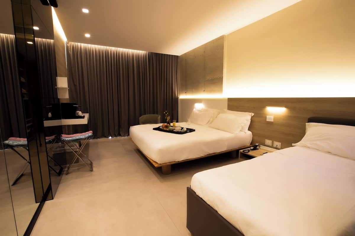 Ein Hotelzimmer mit zwei Betten, einem Schreibtisch mit Stuhl, einem kleinen Tisch mit Frühstücksgegenständen und einem Spiegel.