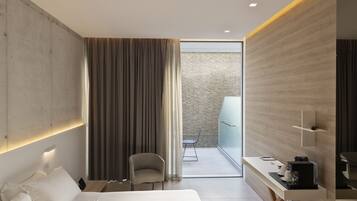 A modern hotel room with a bed, a desk with a coffee maker, a chair, and a view of a balcony.