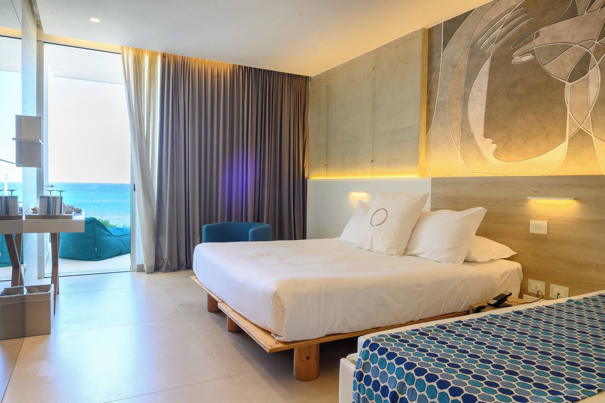 Ein modernes Hotelzimmer mit einem großen Bett, einem Schreibtisch und Meerblick.